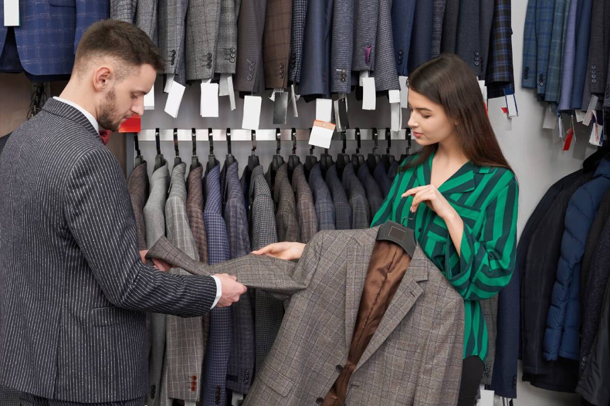 Man and woman examining suit jackets in a clothing store. 